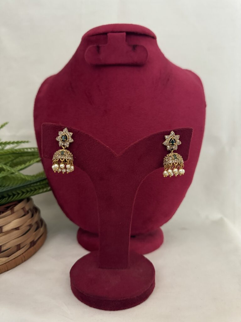 Elegant earrings displayed on a red velvet stand, featuring intricate designs and vibrant colors, showcased by Hautecouture Jewellery for a luxurious and fashionable look.